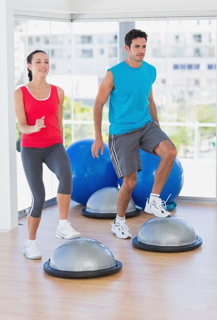 Couple effectuant sur l&#39;équilibre de dôme dans la salle de gym lumineuse