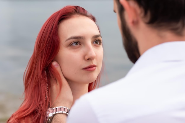 Couple élégant amoureux se promène au bord de la rivière Hipsters mignons se regardent les yeux sur le fond de l'eau Gros plan d'une fille Concept d'amour et de style de vie des jeunes