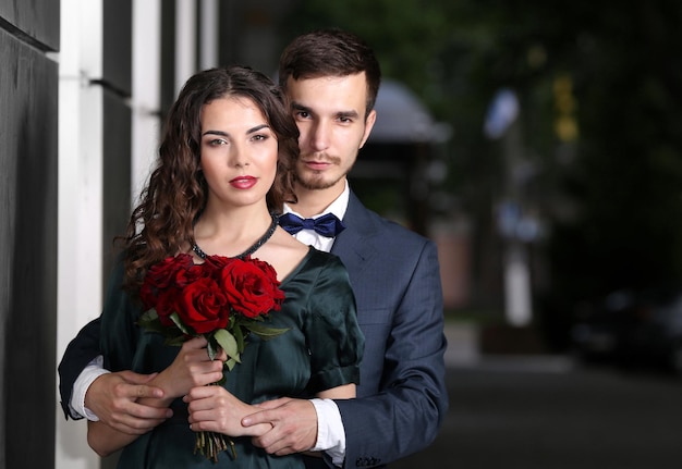 Couple élégant avec bouquet de roses en plein air