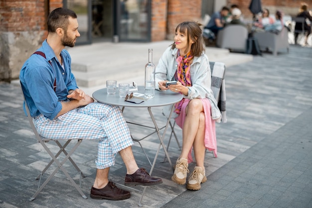Un couple élégant de collègues a une conversation assis à la terrasse d'un café
