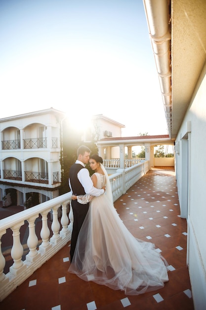 Couple élégant de jeunes mariés heureux posant au coucher du soleil