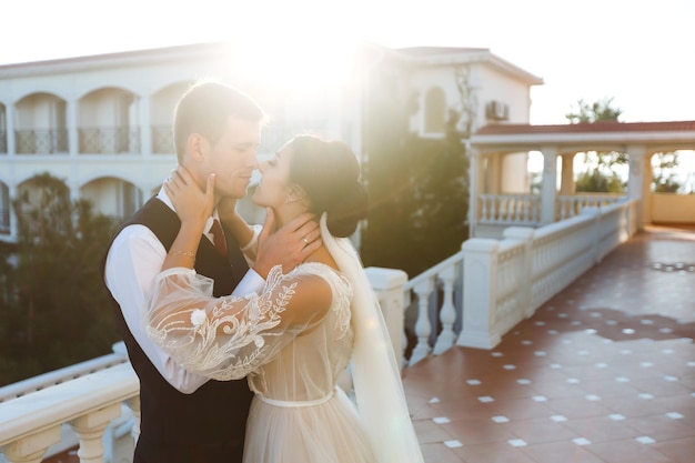 Couple élégant de jeunes mariés heureux posant au coucher du soleil