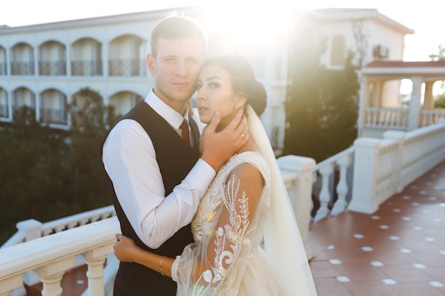 Couple élégant de jeunes mariés heureux posant au coucher du soleil