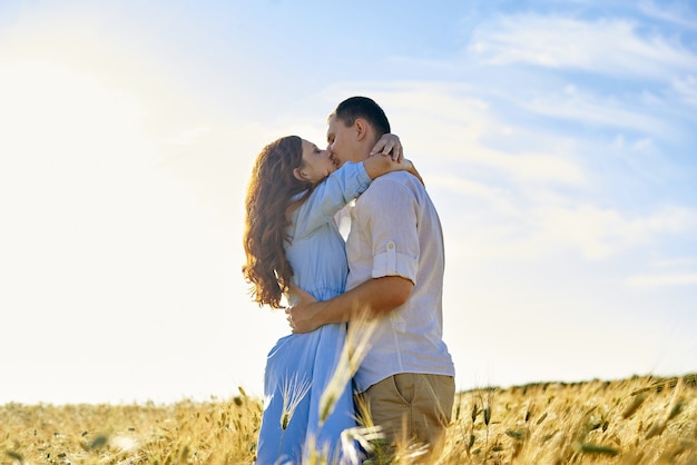 Couple élégant et moderne s'embrassant dans un champ de blé. Une jeune femme embrasse son petit ami et s'embrasse. Le concept de passion et d'amour.