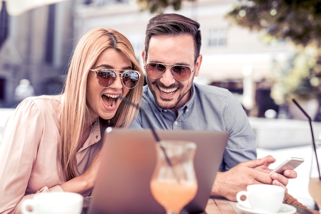 Couple élégant avec ordinateur portable au café