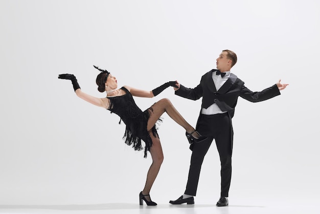 Photo un couple élégant reproduit la danse d'une femme en robe fringe et d'un homme en costume noir dansant isolés.