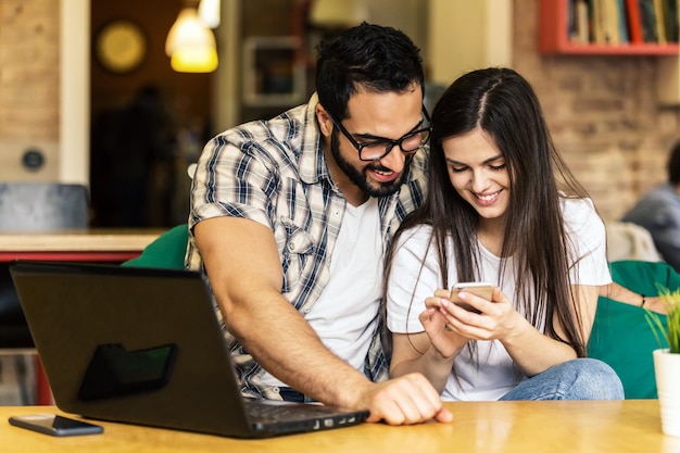 Couple d'employés de bureau regardant des photos prises sur un smartphone