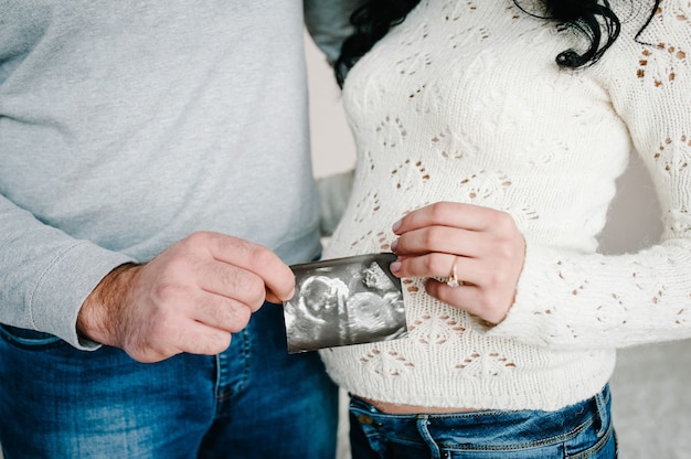 Couple enceinte tenant dans les mains échographie de leur bébé