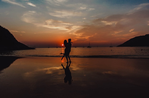 Couple enlacé sur la plage au coucher du soleil