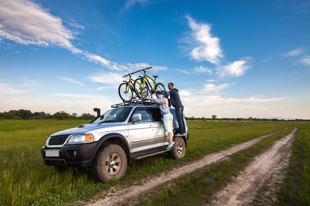 Couple enlevant leurs vélos de la galerie de toit de la voiture