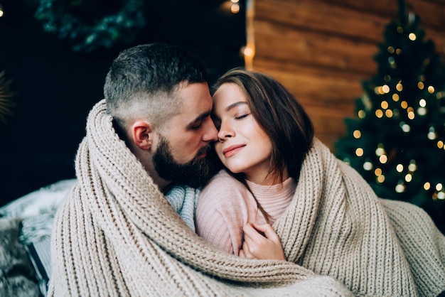 Couple enroulé dans un tapis avec arbre de Noël sur fond