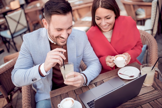 Le couple est assis au café et utilise un ordinateur portable