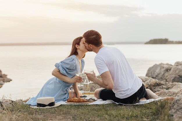 Un couple est assis sur une couverture et s'embrasse.