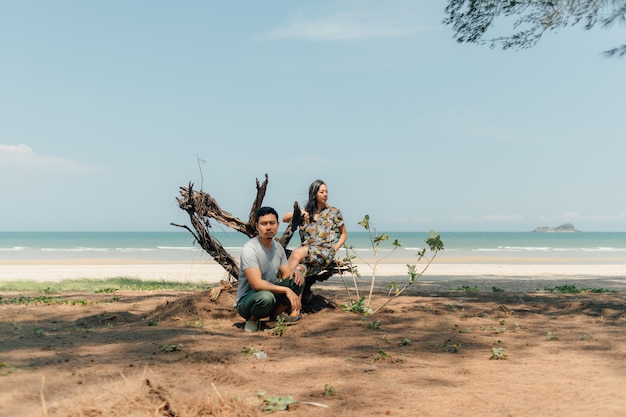 Un couple est assis sur la plage sous les pins.