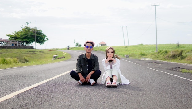 Un couple est assis sur la route devant un champ vert.