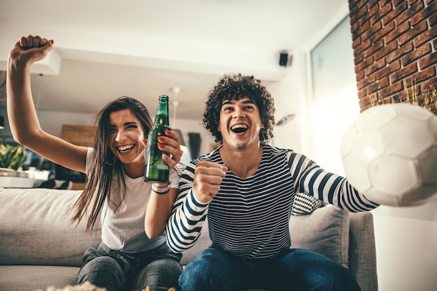 Le couple est fan de jeux sportifs car le football aime passer son temps libre à la maison ensemble. Ils crient et font des gestes pour une victoire.