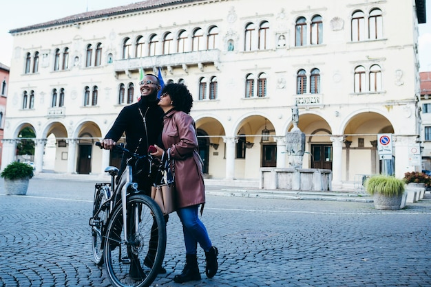 Couple ethnique noir avec des vélos dans les rues d'une ville italienne.