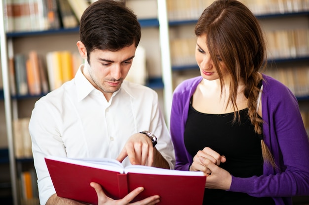 Couple d'étudiants lisant dans une bibliothèque