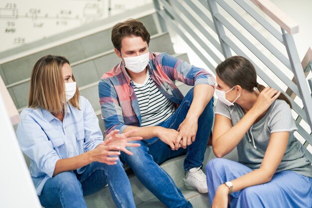 Couple d'étudiants portant des masques se relaxant sur le campus