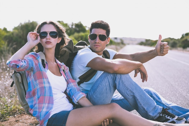 Couple faisant de l'auto-stop sur la route de campagne