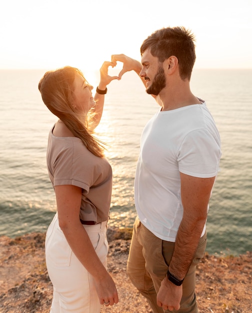 Couple faisant un coeur avec leurs doigts au coucher du soleil