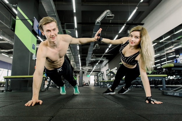 Couple faisant des pompes à l'entraînement dans la salle de gym. Couple sportif faisant des pompes et donnant des high five. Intérieur du gymnase.