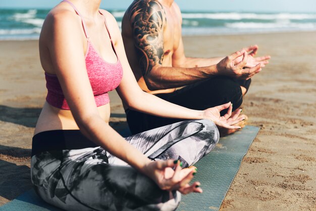 Le couple fait du yoga à la plage