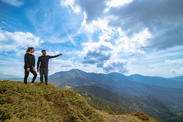 Le couple fait des gestes sur la montagne avec un paysage nuageux pittoresque