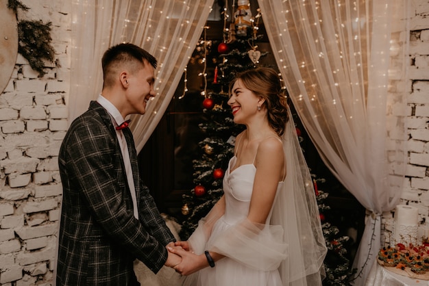 Couple de famille heureux célébrant le Nouvel An et Noël à l'arbre de Noël décoré et des guirlandes