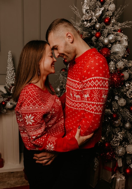 Couple de famille heureux célébrant le Nouvel An et Noël à l'arbre de Noël décoré et des guirlandes