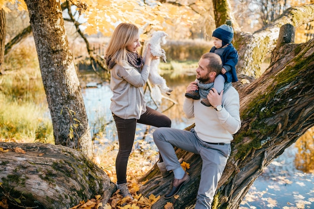 Couple de famille heureux avec leur petit enfant et chiot dans le parc automne en journée ensoleillée.