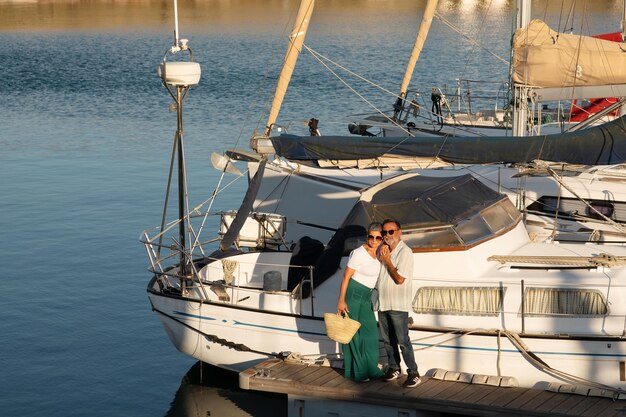 Couple de famille senior debout près d'un yacht de luxe embrassant l'extérieur