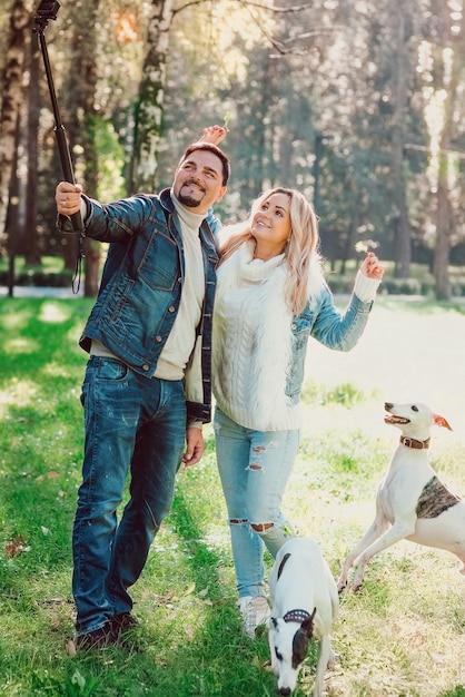 couple femme et homme dans des vêtements en jean marchant avec des chiens whippets en plein air