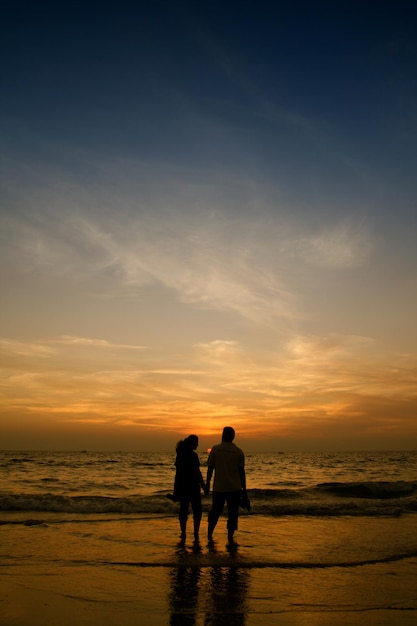 Couple de femme et d'homme restant près de la mer et regardant le coucher du soleil