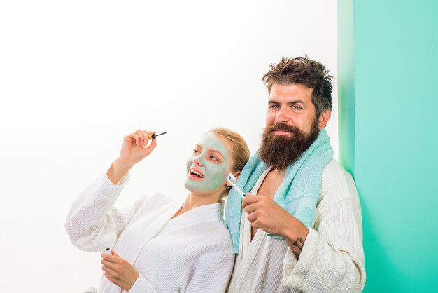 Couple femme et mari se préparant au travail fille avec masque cosmétique sur le visage appliquant le mascara le matin