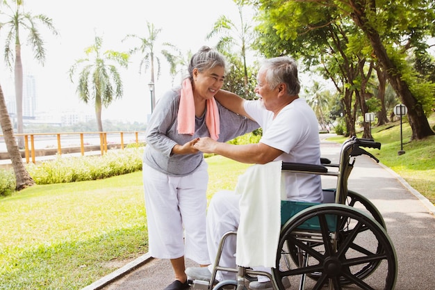 Couple femme prend soin de la santé en fauteuil roulant mari malade avec amour bonheur et durable dans le jardin