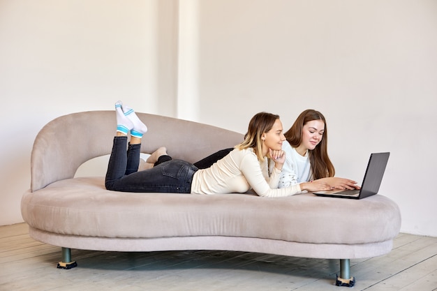 Un couple de femmes sur un canapé regarde des films avec un ordinateur portable