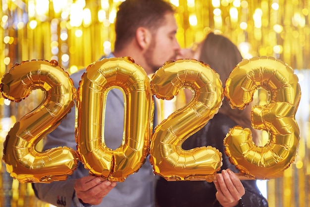 Couple à la fête du nouvel an avec des ballons d'or