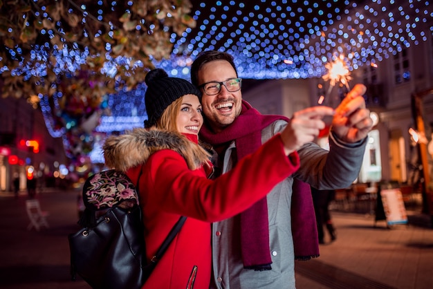 Couple avec feux de Bengale appréciant la fête de Noël dans la rue.