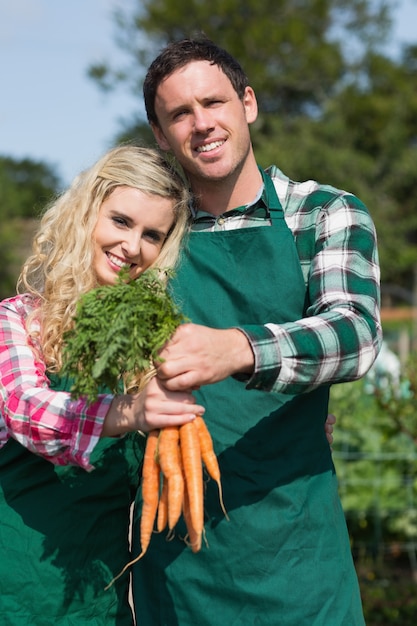 Couple fier présentant des carottes