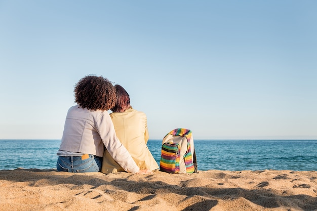 Couple de filles gays assis sur la plage