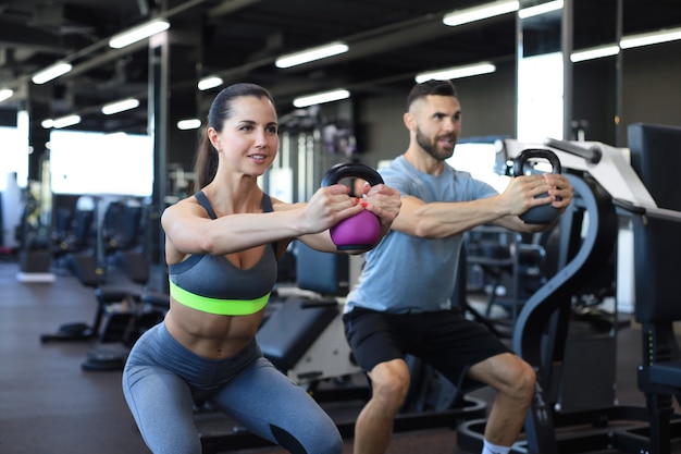 Un couple en forme et musclé s'est concentré sur le levage d'un haltère lors d'un cours d'exercice dans une salle de sport.