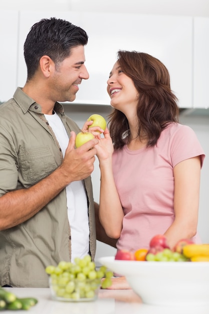 Couple avec des fruits qui se regardent dans la cuisine