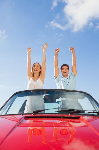 Couple gai debout dans le cabriolet rouge