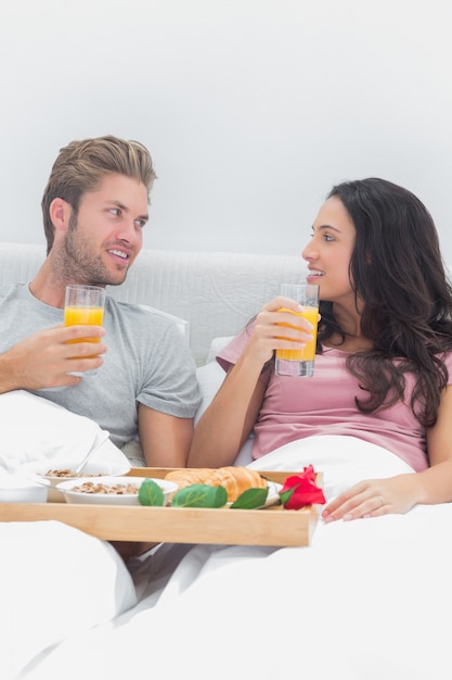 Couple gai prenant son petit déjeuner au lit