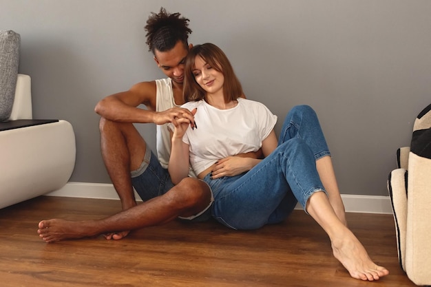 Un couple un gars et une fille sont assis à la maison sur le sol contre un mur gris