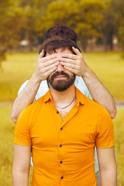 Photo couple gay dans le parc jeune homme couvrant les yeux de son petit ami