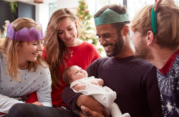 Couple gay avec une petite fille adoptée célébrant le premier Noël avec des amis