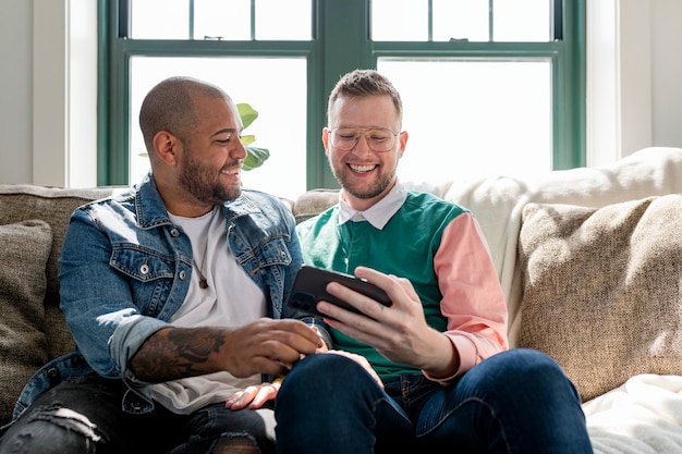 Couple gay prenant des selfies, assis sur un canapé à la maison