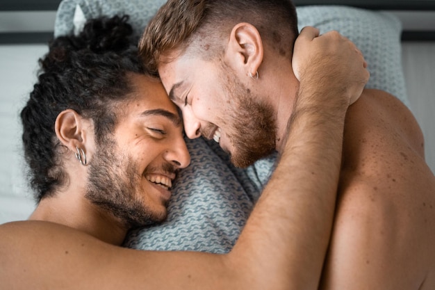 Photo couple gay se caressant dans le lit en se regardant
